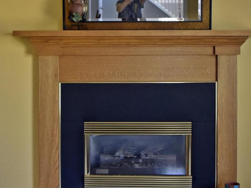 Haard met lichte houten mantel en gouden details
